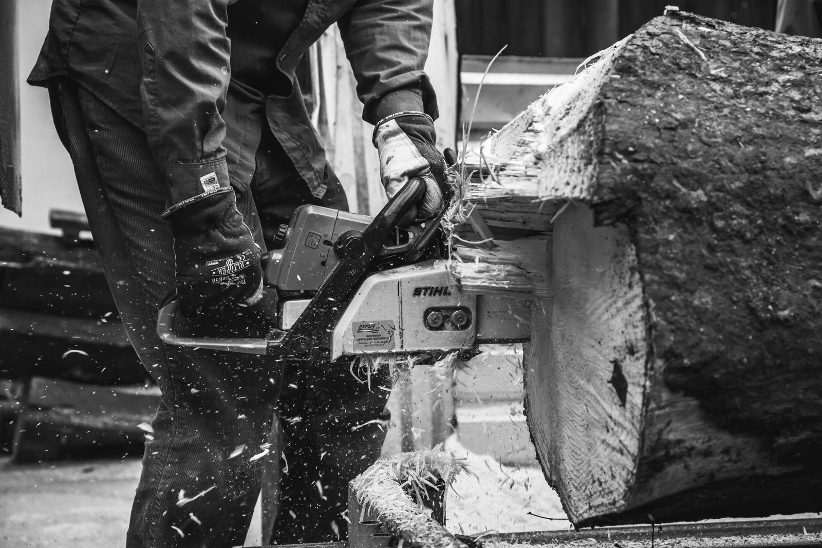 A person cutting a log with a chainsaw outdoors