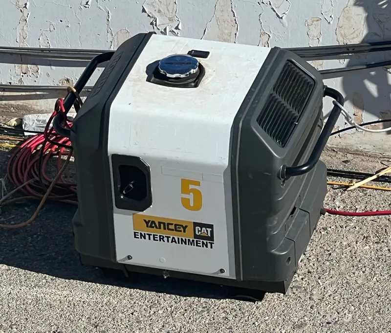 A small enclosed inverter generator with a rental-company decal, standing outdoors