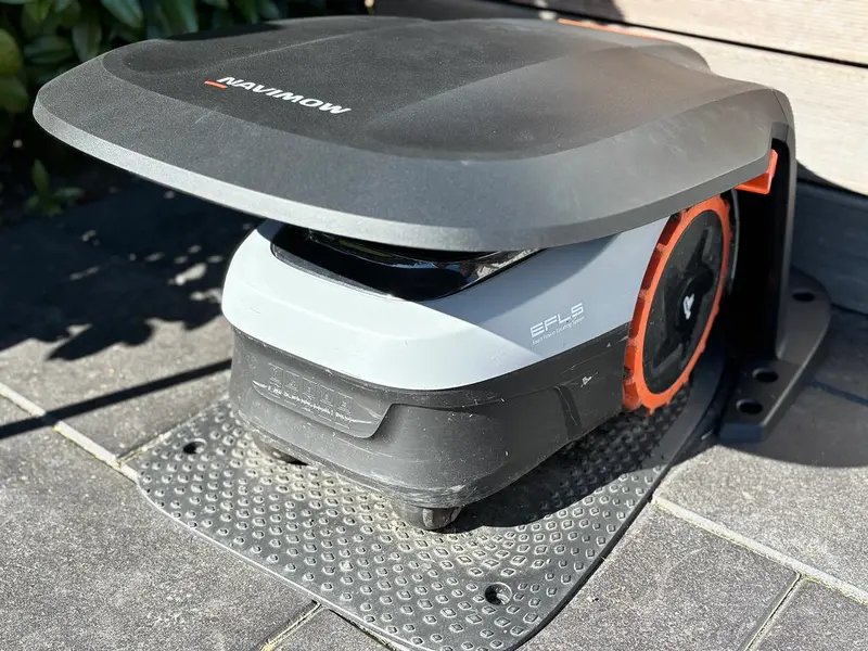 A robotic lawn mower resting in a garage next to its dock